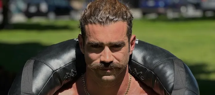 Dom in a park, a heavy sandbag across his shoulders